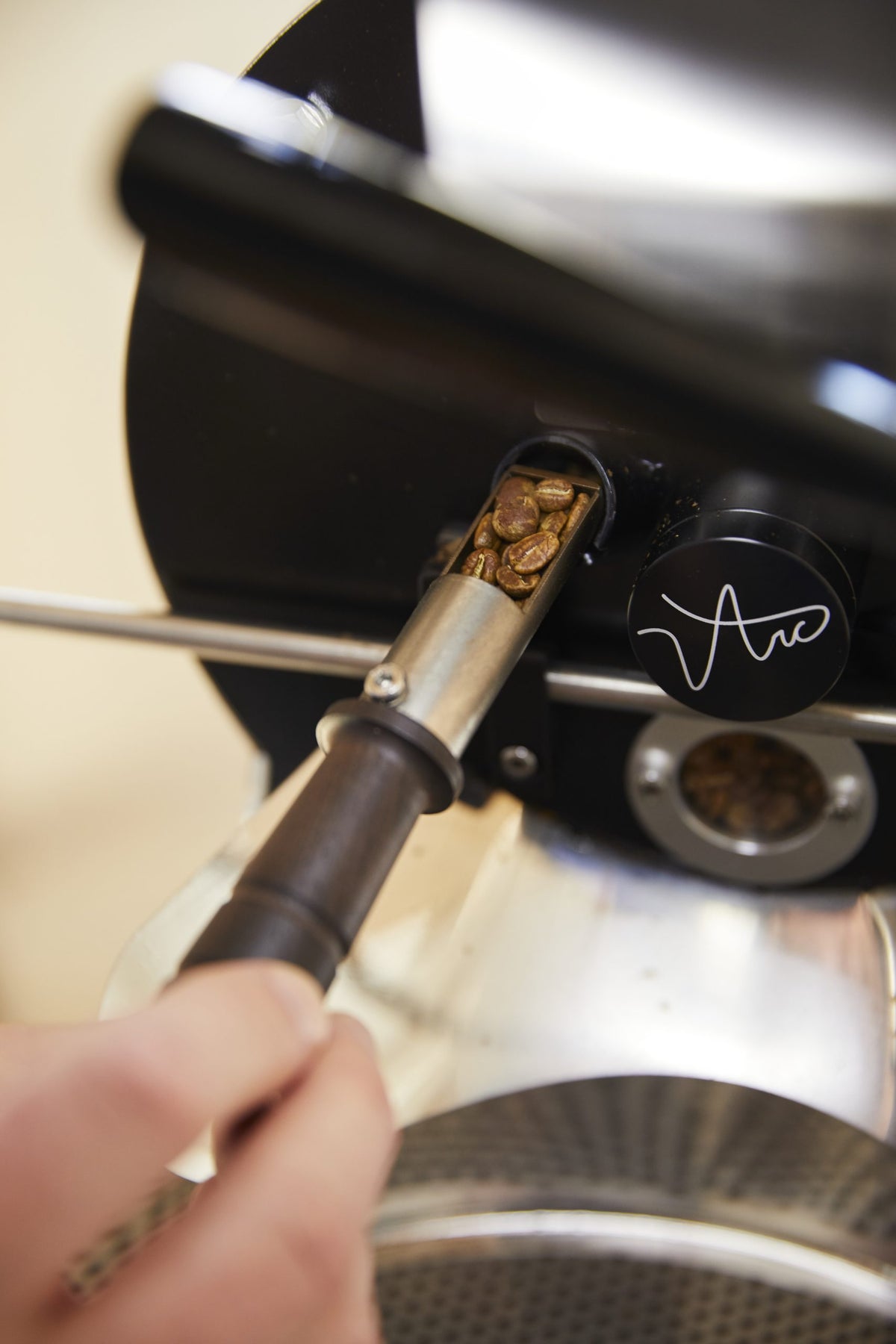 Trier pulling out beans from the roasting drum to monitor progress.